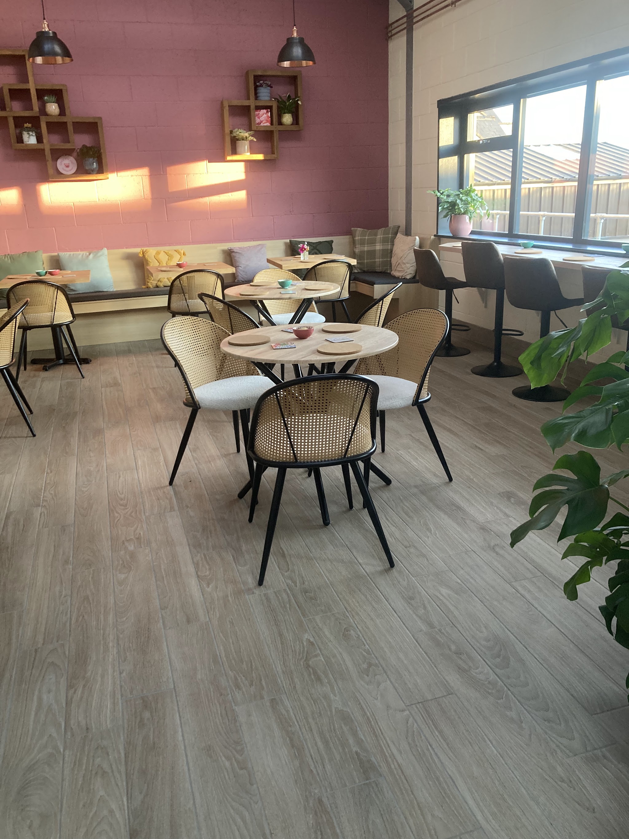 Our cosy café interior with pink walls, small tables and window seating