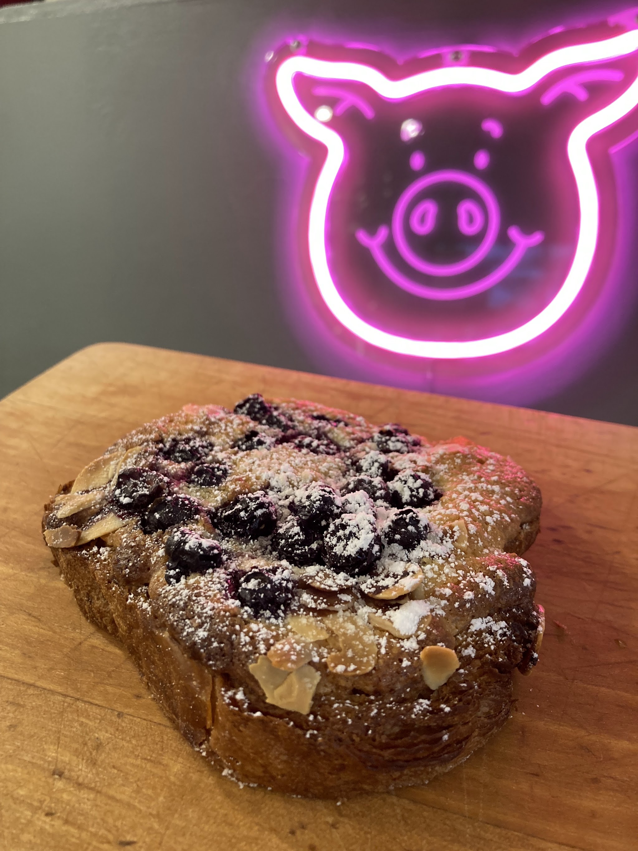 Berry-topped bake on the counter beneath our pink neon pig sign